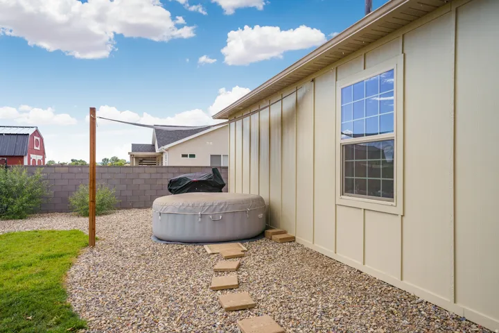 Board and batten siding, grid-pattern window, gravel hardscaping, concrete block fence, and stepping stone pathway