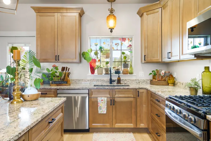 Light-toned cabinetry, granite-finish countertops, stainless steel dishwasher, stainless steel range, and a built-in microwave
