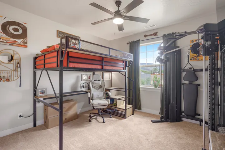 Carpeted room featuring a ceiling fan, a window with exterior views, and a multi-functional built-in loft bed with a desk