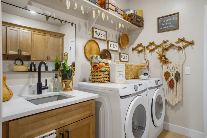 Integrated laundry room with wood-finish cabinetry, white countertop, and a built-in sink with a matte black faucet