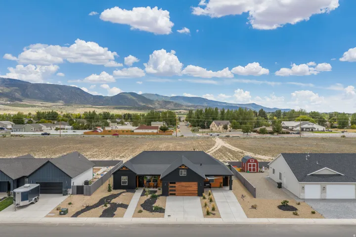 Modern exterior with a dark facade, wood-finish garage doors, and a concrete driveway