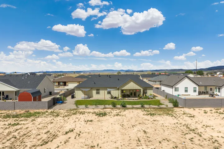 Expansive backyard with a covered patio, manicured lawn, and mature plantings
