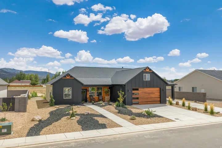 Contemporary exterior with dark vertical siding, a wood-finish garage door, and a covered front entry