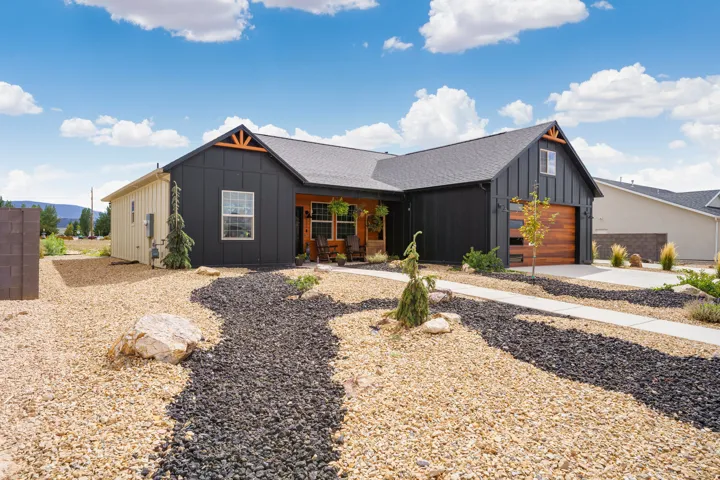 Modern exterior featuring black vertical siding, wood-finish garage door, and a covered porch