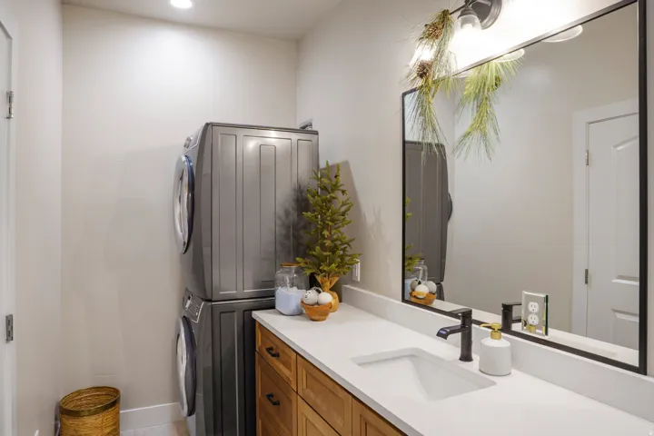 Modern bathroom featuring a wood-finish vanity with an undermount sink, white quartz countertop, and matte black faucet