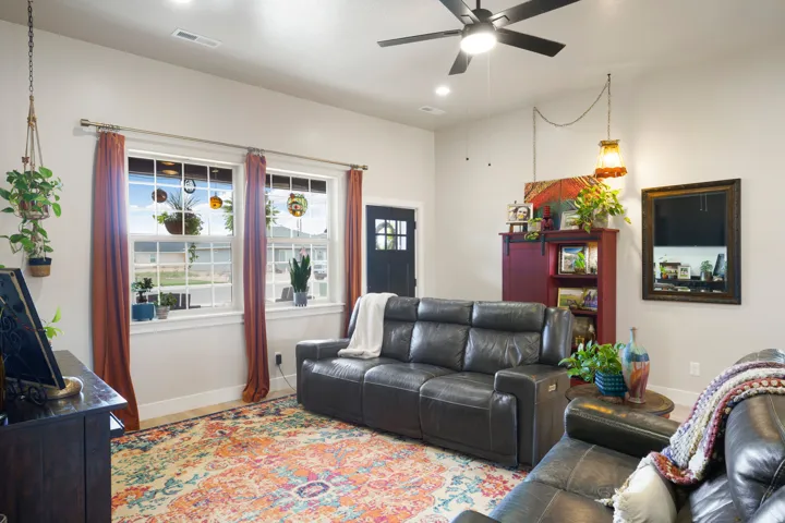 Spacious living area featuring large windows, recessed lighting, and a ceiling fan