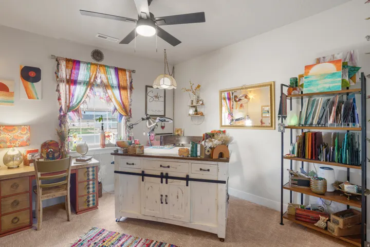 Recessed window framing exterior views, overhead ceiling fan with lighting, built-in shelving unit with wood-finish shelves, wall-mounted display shelving