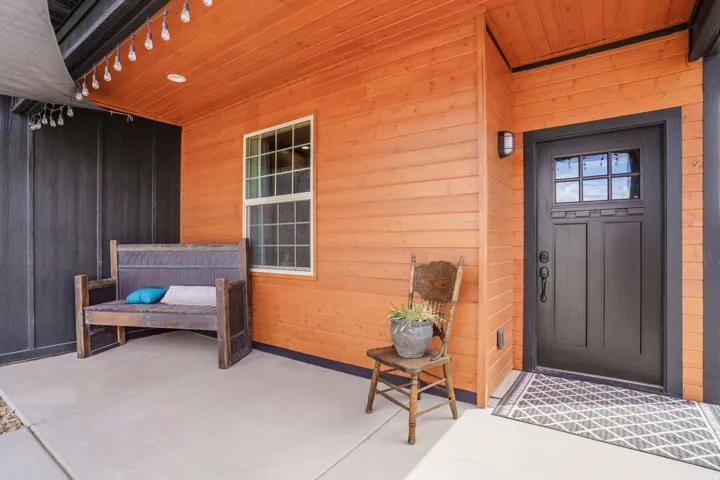 Covered concrete patio featuring shiplap siding, a wood plank ceiling, and an exterior wall lantern