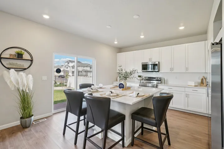 Kitchen featuring an island with seating, white cabinetry, stainless steel appliances, and a sliding glass door to the backyard