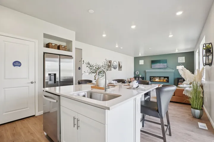 Kitchen island with an undermount stainless steel sink, a stainless steel dishwasher, and white cabinetry