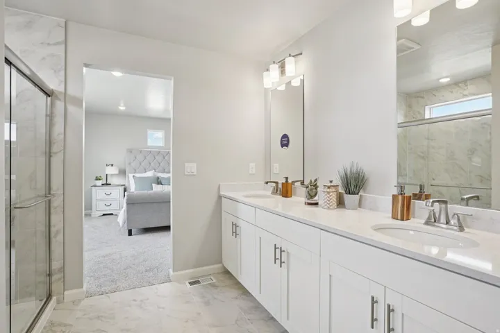 Double vanity with undermount sinks, stone countertops, and ample white cabinetry