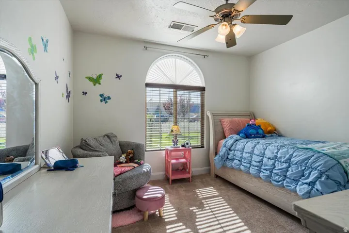 Arched window with blinds, ceiling fan with integrated lighting, and neutral wall tones