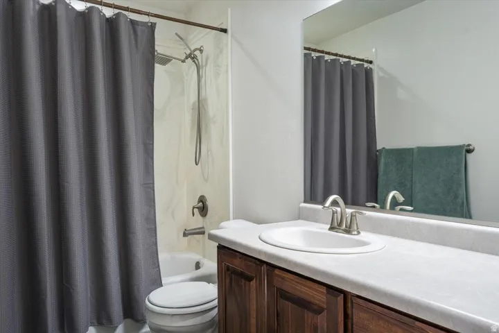 Bathroom featuring a dark wood-finish vanity, white countertop, integrated sink, and an undermount bathtub with a shower