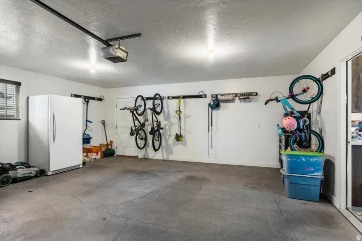Spacious garage featuring a concrete floor, built-in overhead lighting, a garage door opener system, and a window with blinds