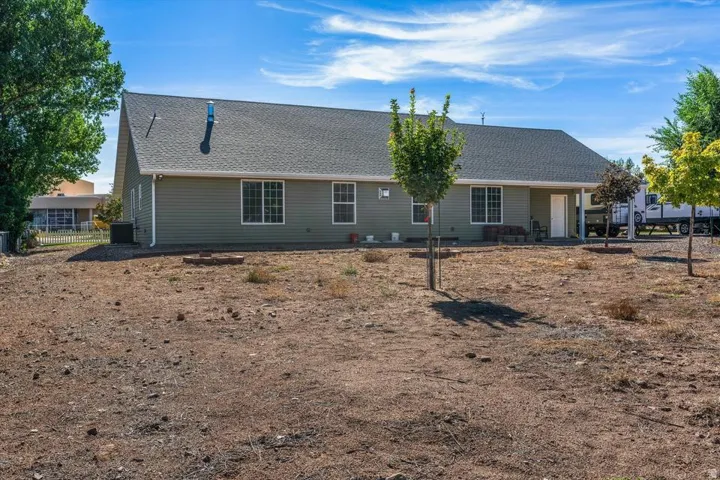 Light green siding exterior with multiple windows, a covered patio, and a dark shingle roof
