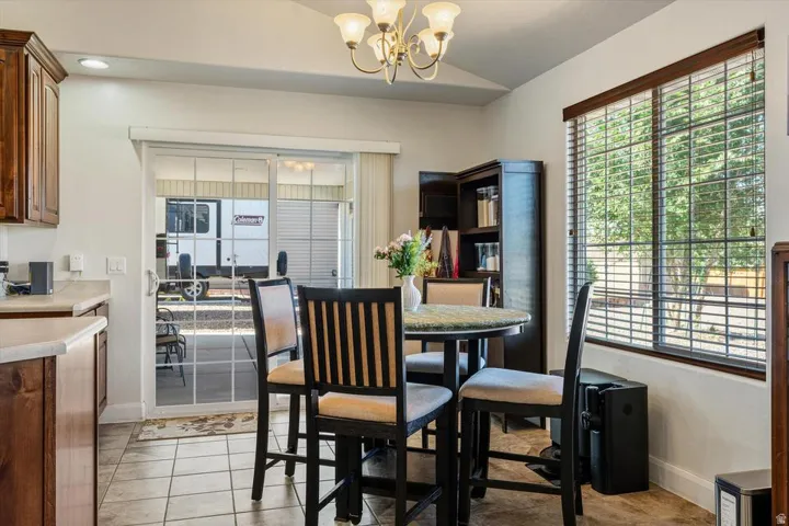 Vaulted ceiling, recessed lighting, tile flooring, wood-finish cabinetry, and sliding glass door