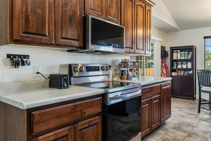 Kitchen featuring wood cabinetry, light-toned countertops, stainless steel range, and a built-in microwave