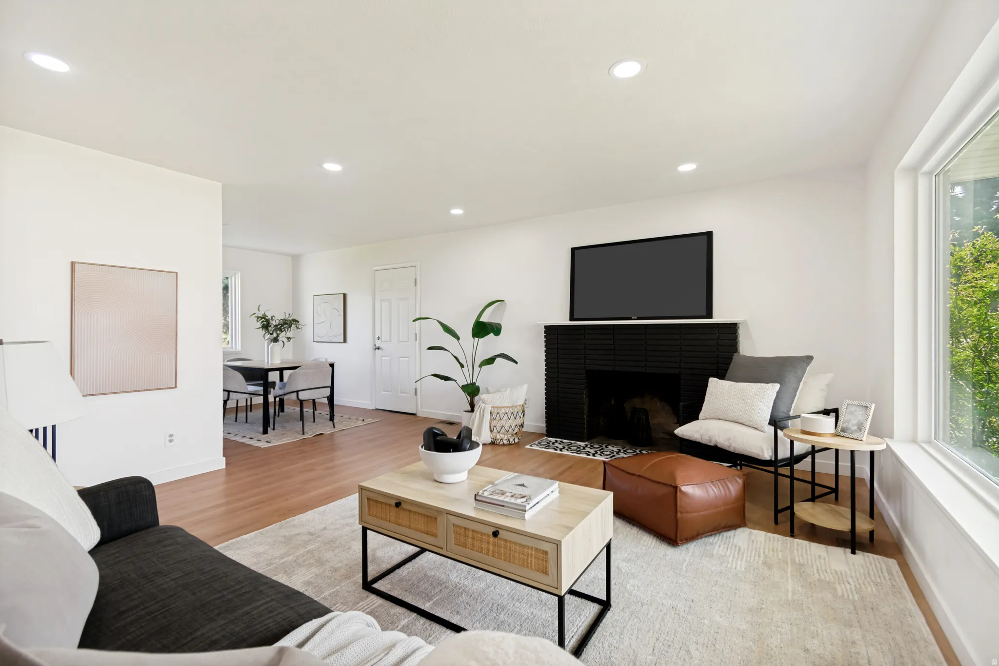 Recessed lighting, wood-finish flooring, white walls, black tile fireplace, and a large window
