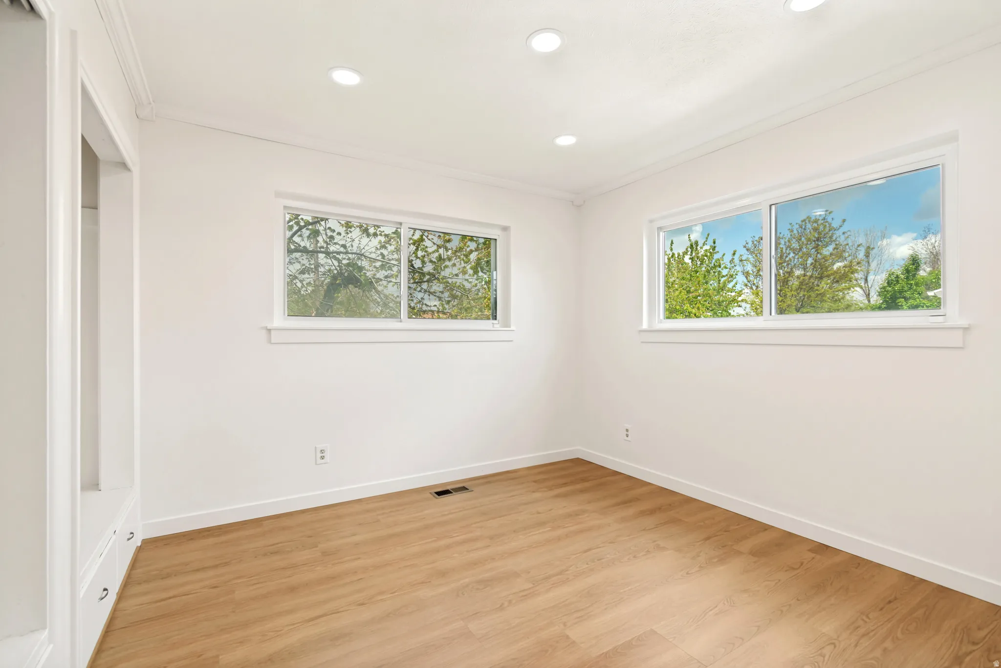 Wood-finish flooring, recessed lighting, and built-in cabinetry featuring drawer pulls
