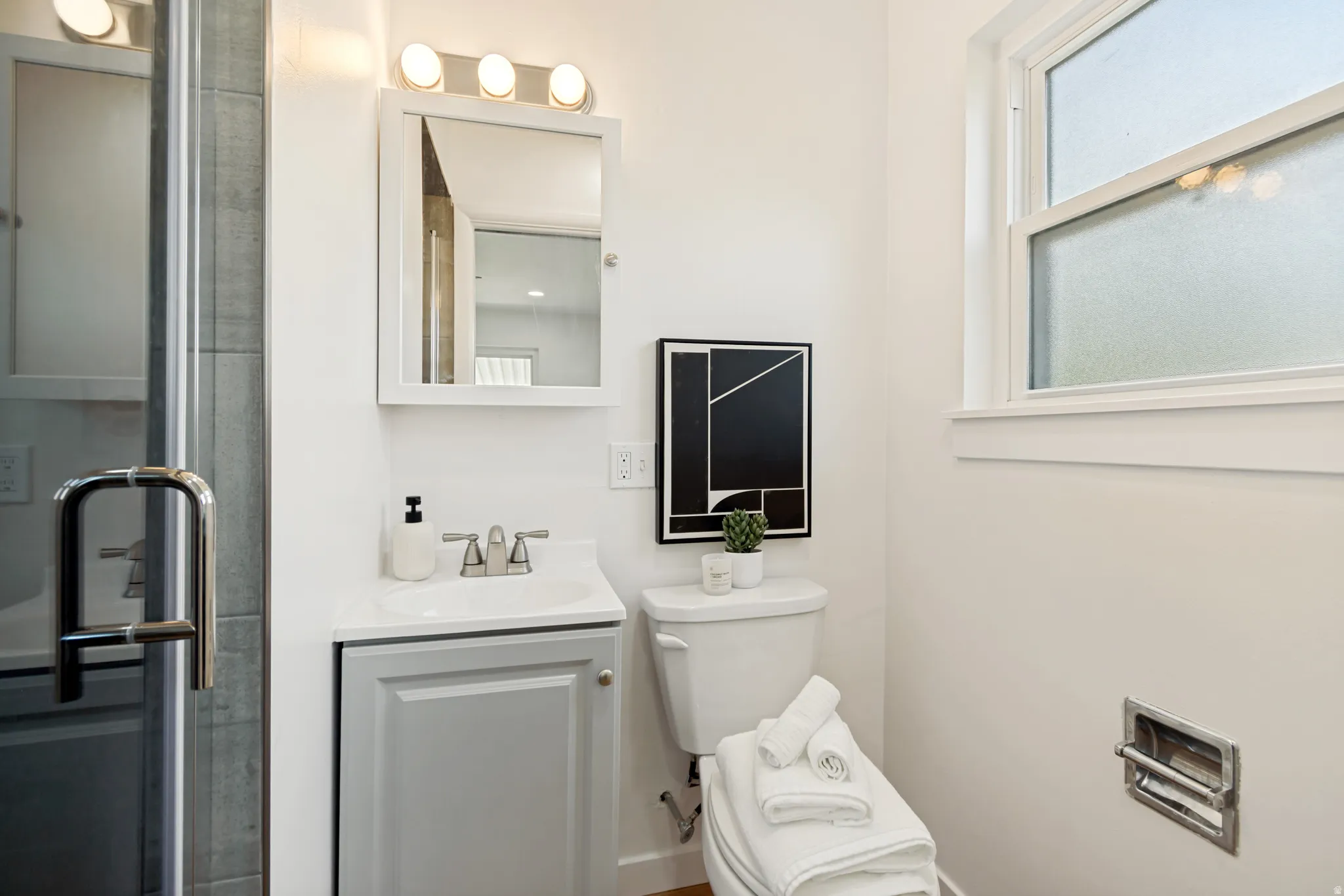 White vanity with a single basin sink, brushed nickel faucet, and integrated storage