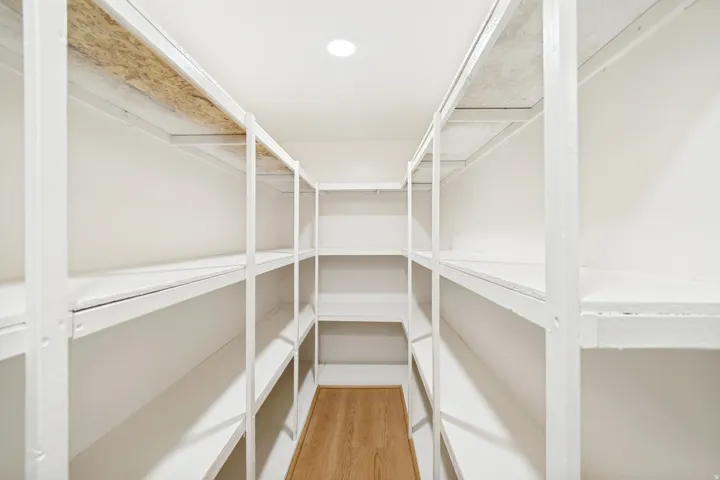 Walk-in storage area with extensive white shelving