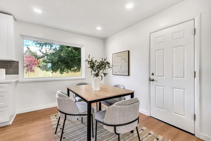 Recessed lighting, wood-finish flooring, white paneled door, and a large window with a white frame