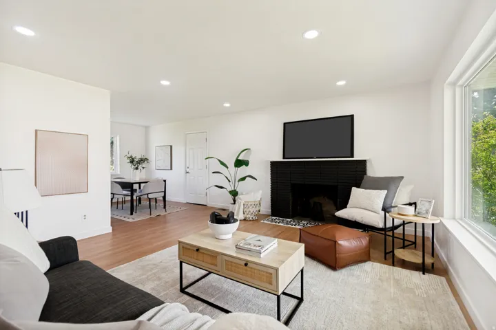 Recessed lighting, wood-finish flooring, white walls, black tile fireplace, and a large window