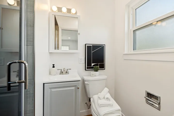 White vanity with a single basin sink, brushed nickel faucet, and integrated storage