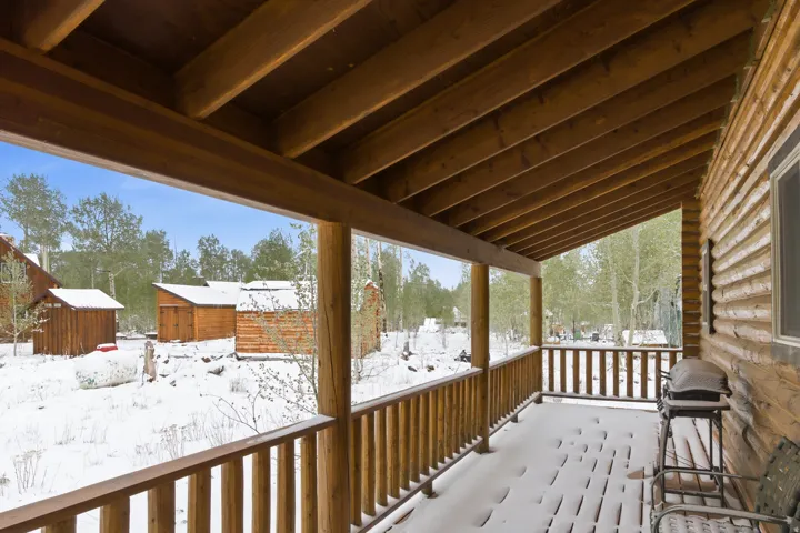 Expansive covered porch with wood railing and exposed rafter ceiling