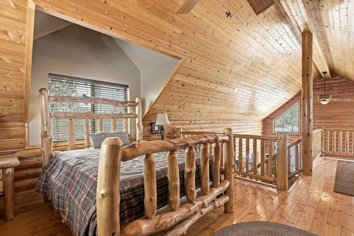 Wood-paneled walls and ceiling, wood-finish flooring, accent window, exposed wood beam, ceiling fan