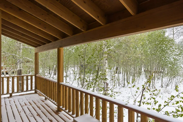 Wood deck with a slatted railing, supported by timber posts and an exposed beam ceiling