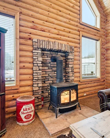 Wood-paneled interior walls, stone fireplace surround, and a cast iron wood-burning stove with a stone hearth