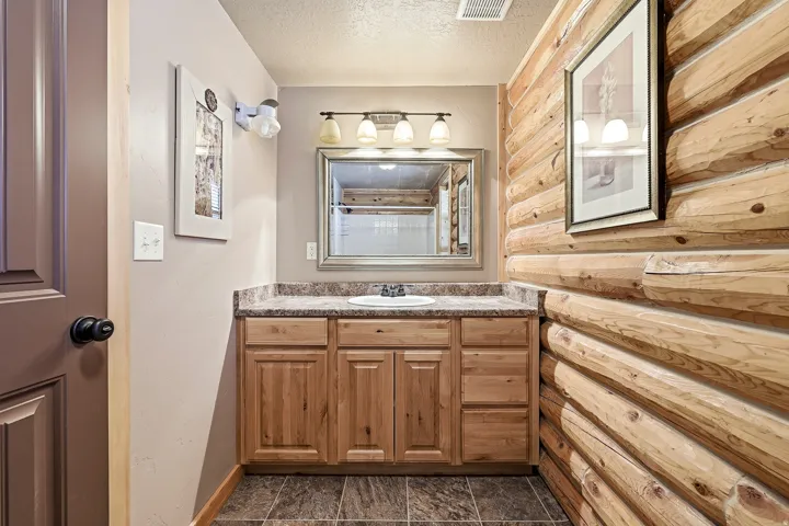 Wood-finish vanity with a single basin sink and speckled countertop