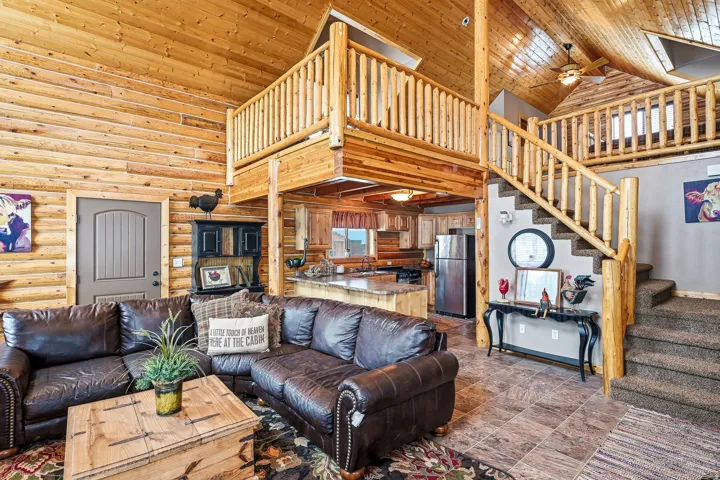 Wood-paneled walls and ceiling, exposed wood beams, and a wood staircase with a loft overlook