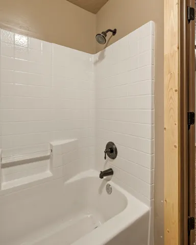Bathtub with integrated shelving, white subway tile-patterned surround, and oil-rubbed bronze fixtures