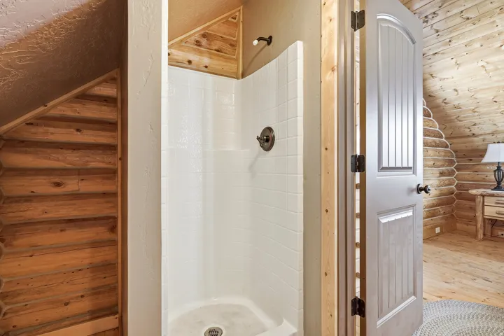 White shower stall with a bronze-finish shower fixture