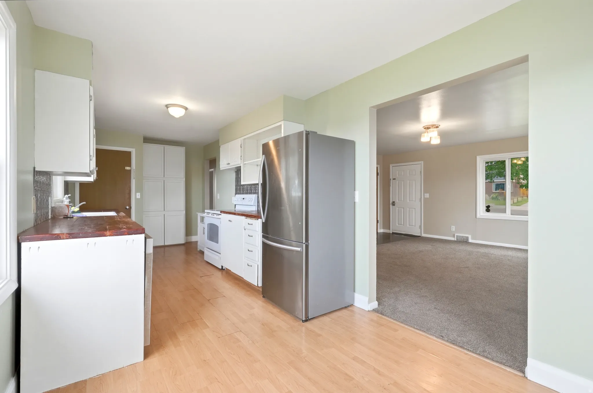 Kitchen featuring wood-finish flooring, white cabinetry, and stainless steel refrigerator