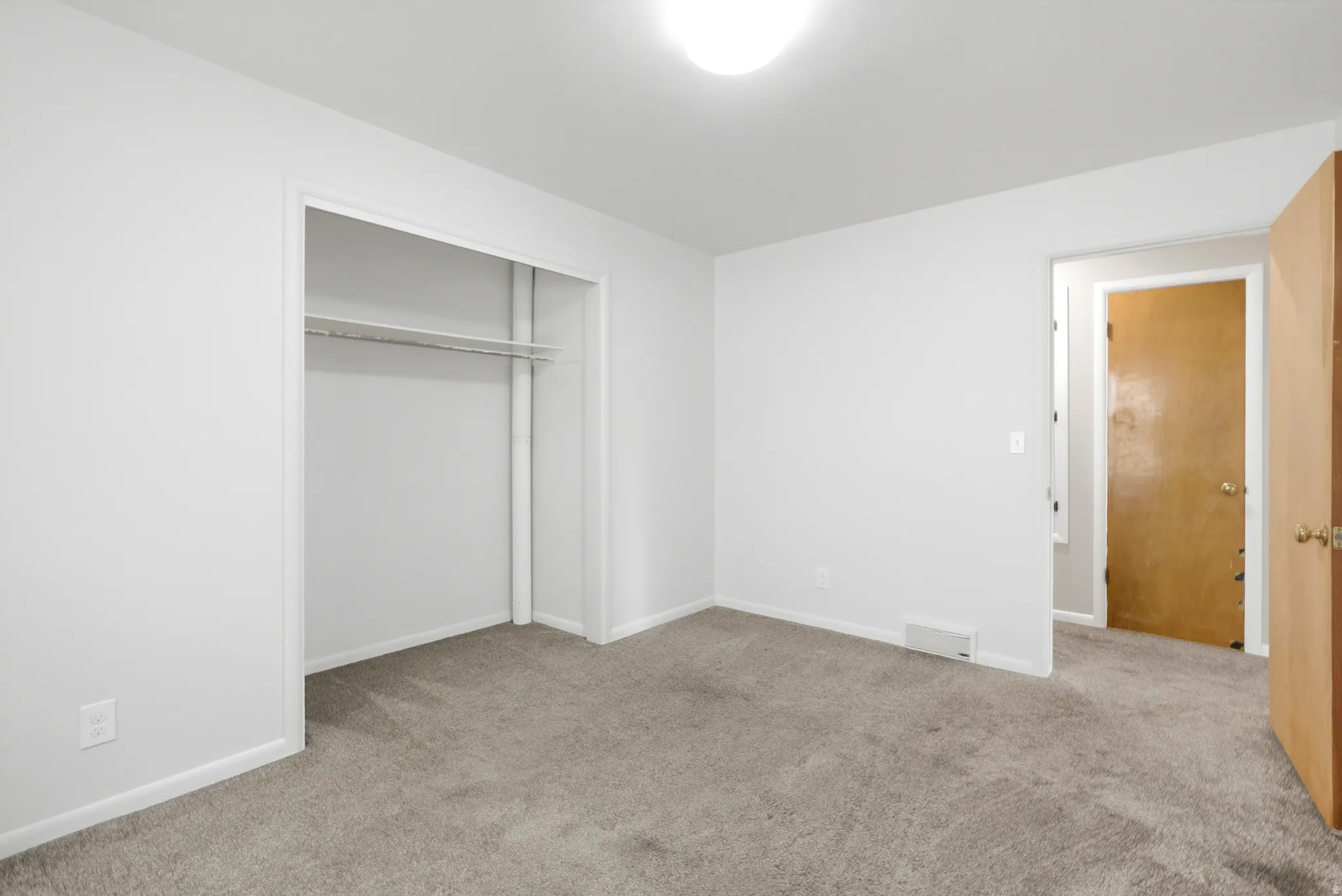 Neutral wall finishes, plush grey carpeting, and overhead lighting