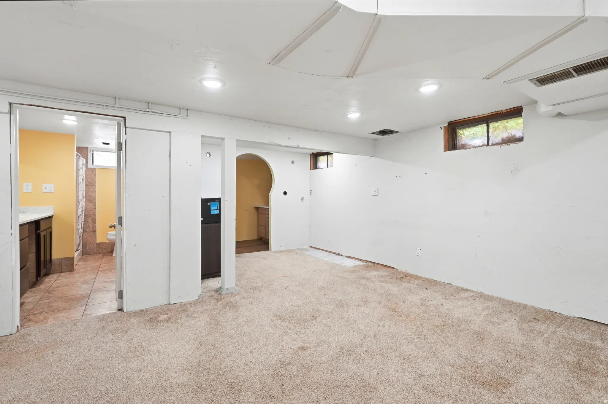 Recessed lighting, arched doorway, exposed ceiling ducts, and a window