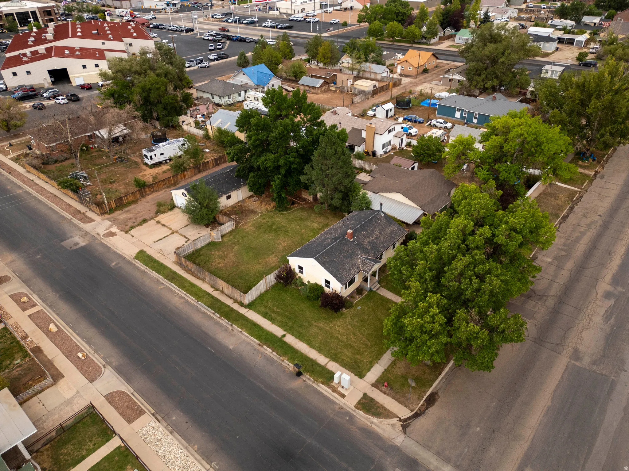 Corner lot property featuring a detached garage, mature trees, and a grassy yard
