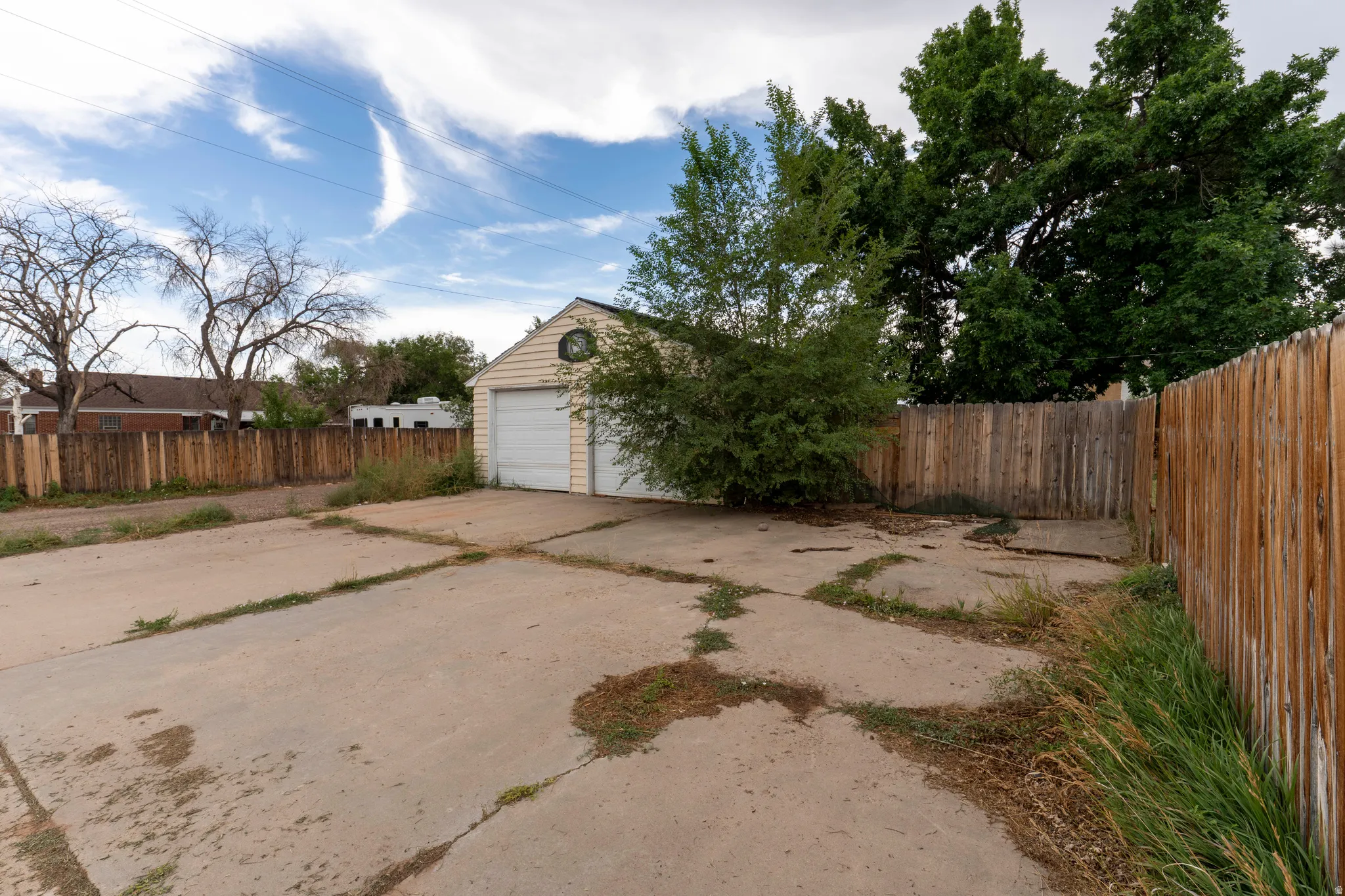 Detached garage with two roll-up doors, wood-paneled siding, and a concrete pad