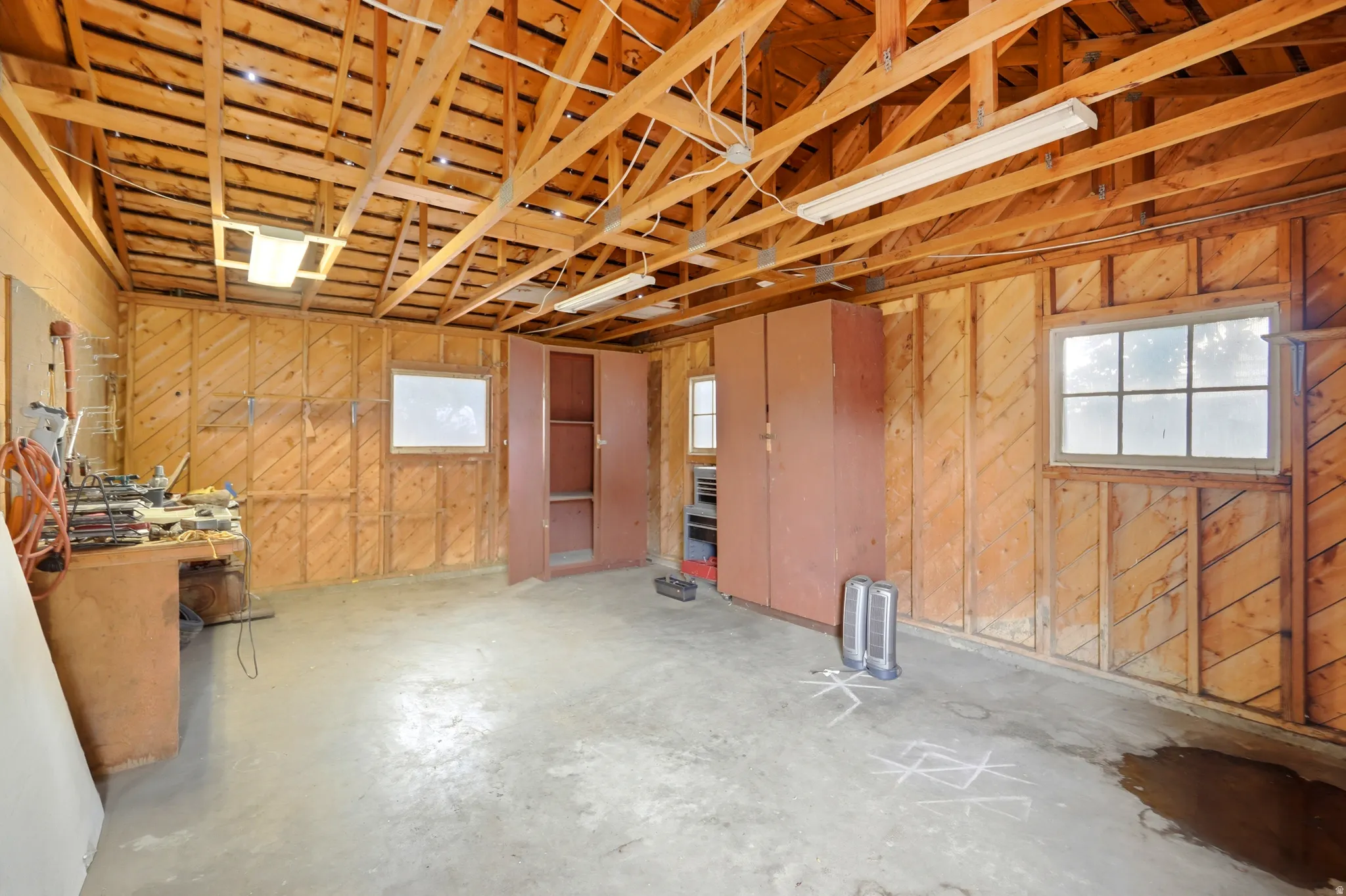 Exposed wood beam ceiling, concrete flooring, built-in storage cabinetry, and multiple windows