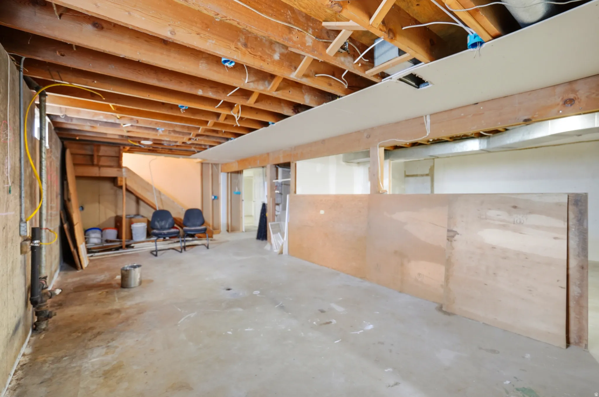 Exposed wood ceiling joists with visible wiring and plumbing