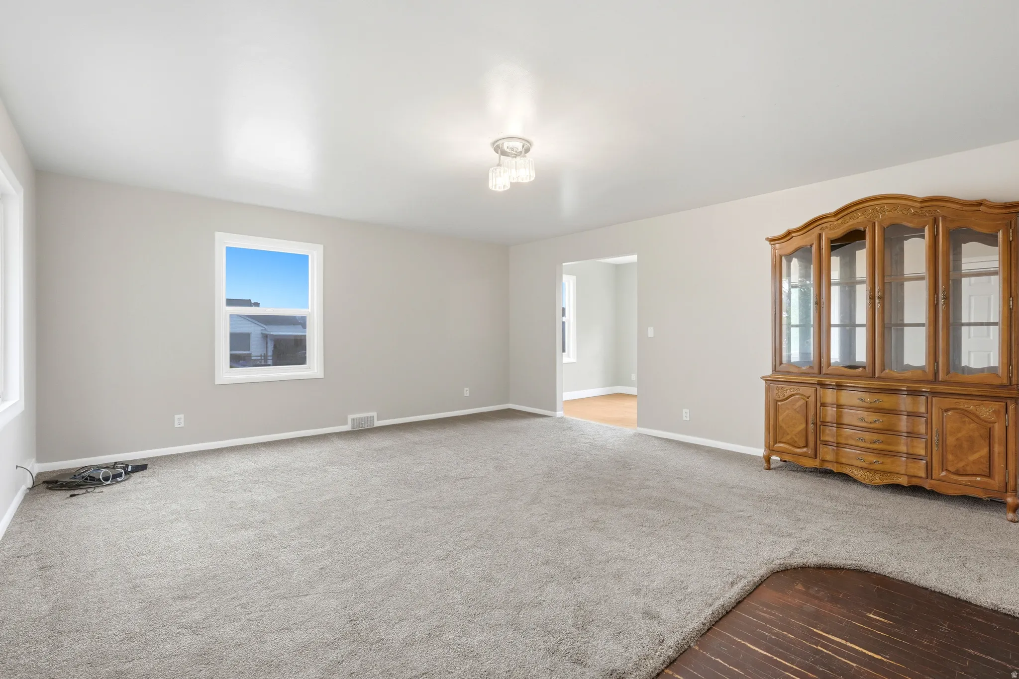 Expansive carpeted area with neutral wall tones and a ceiling-mounted light fixture