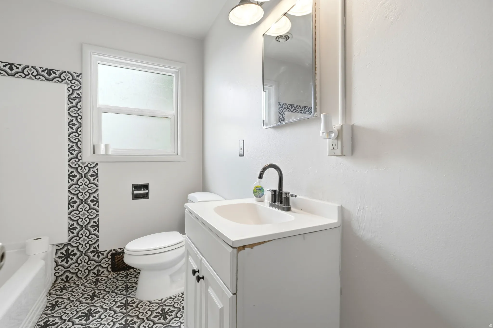 White vanity with a single basin sink, black faucet, and two-door cabinet storage