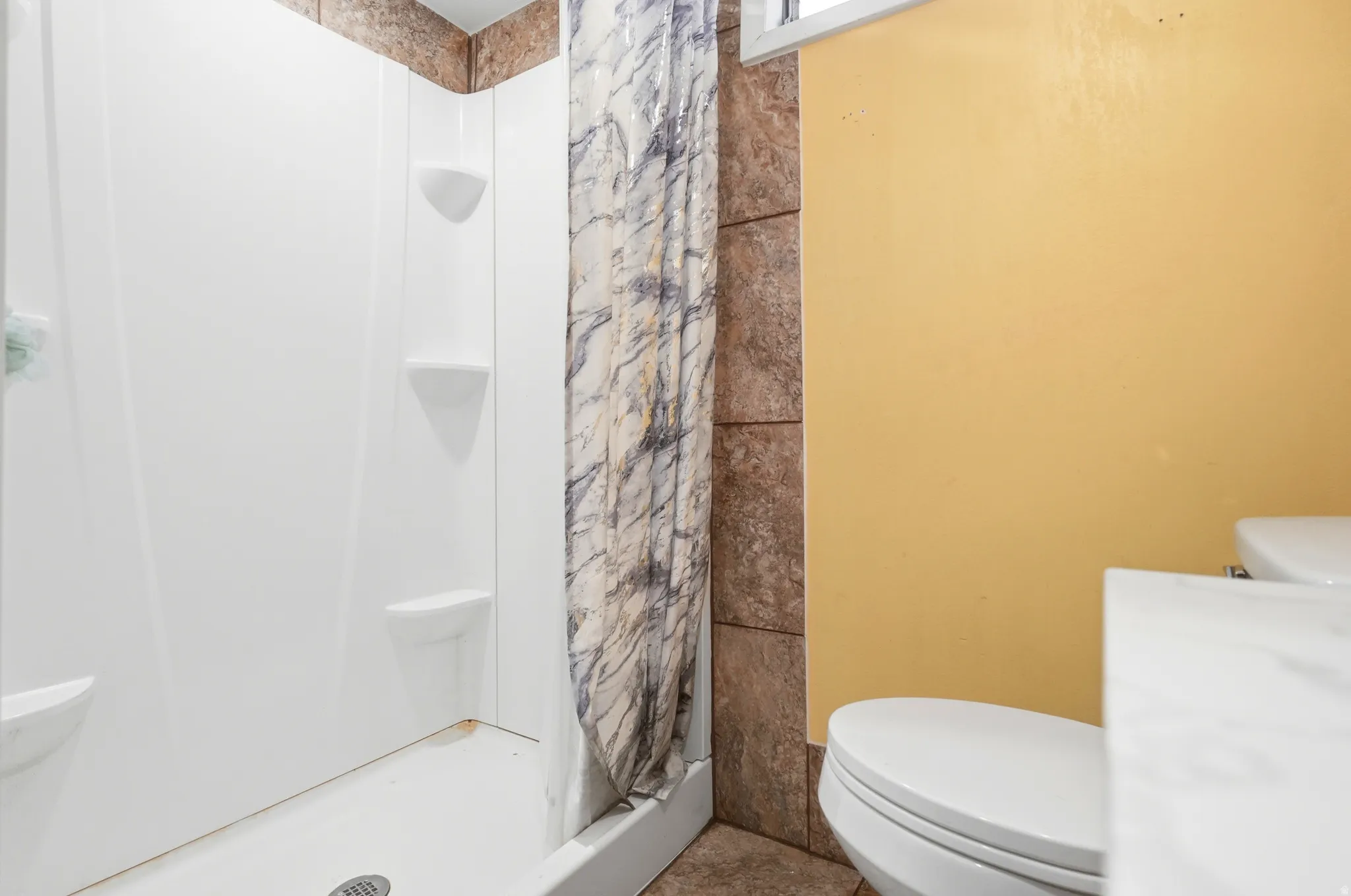 White shower surround with integrated shelving, tiled shower wall, and a window