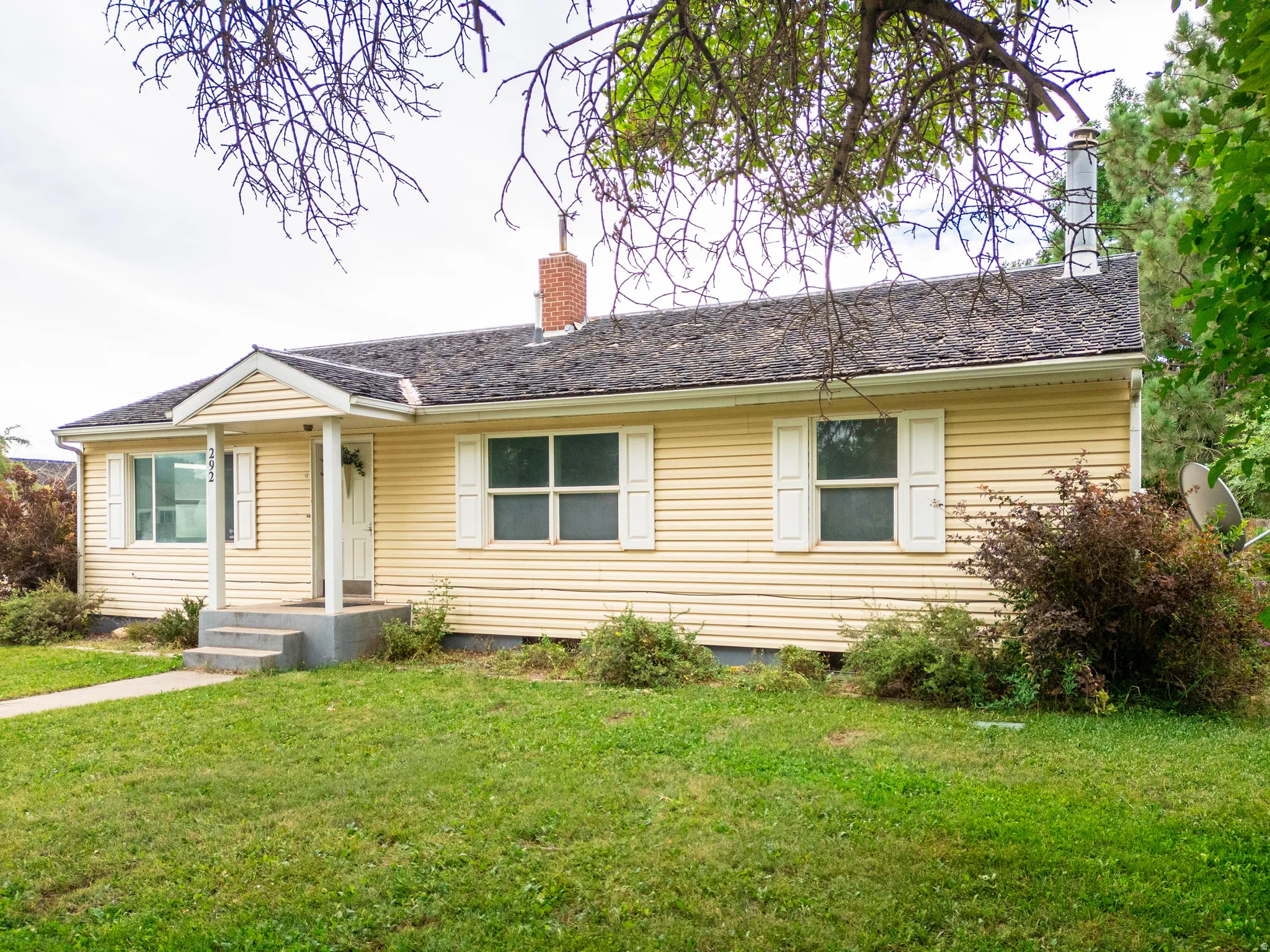 Exterior featuring yellow siding, white window shutters, and a covered porch entry