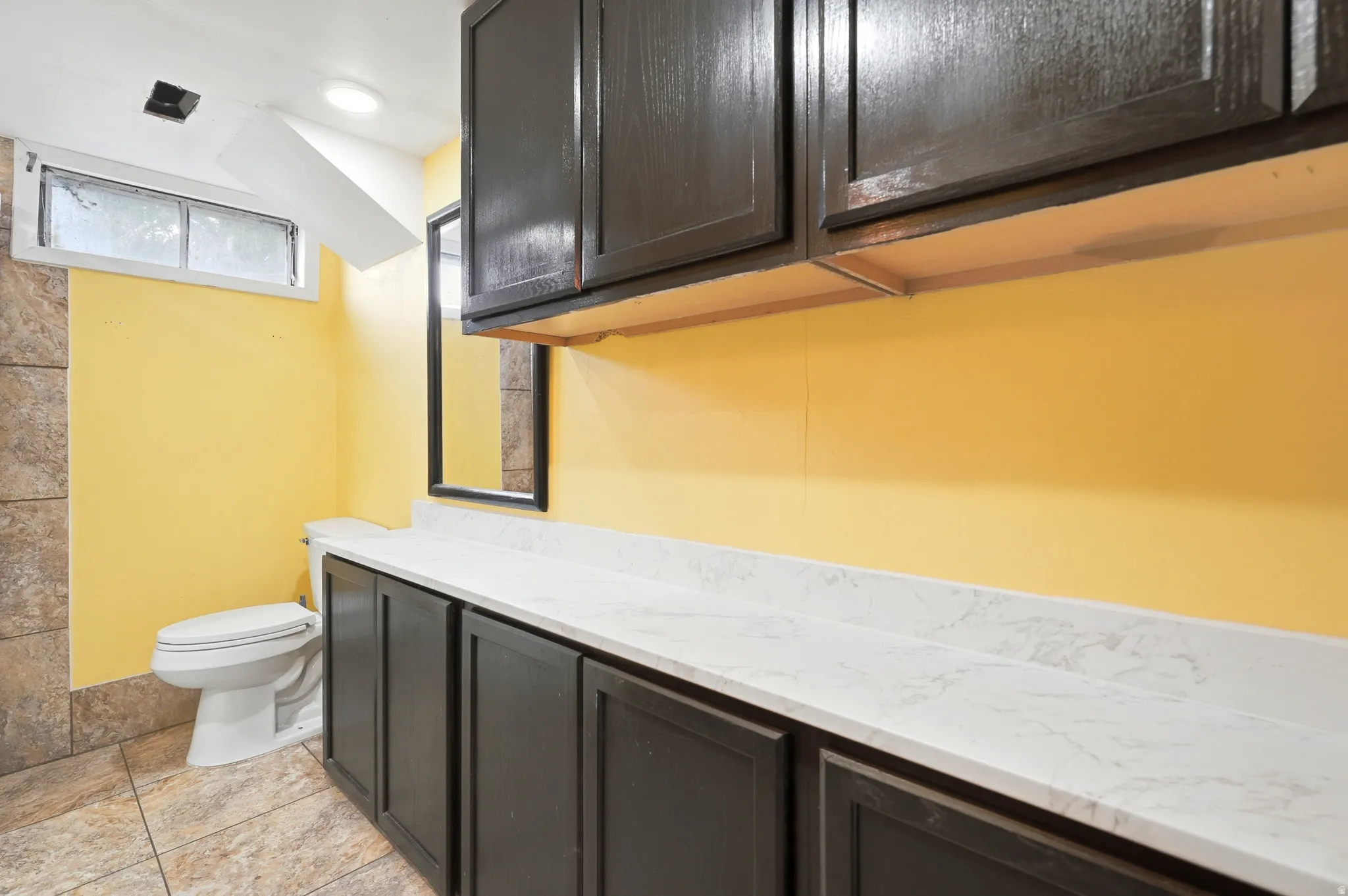 Built-in vanity with extensive counter space, dark wood-finish cabinetry, and white countertop