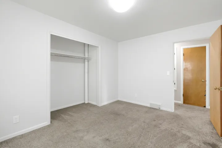 Neutral wall finishes, plush grey carpeting, and overhead lighting