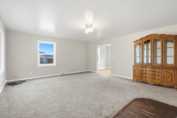 Expansive carpeted area with neutral wall tones and a ceiling-mounted light fixture